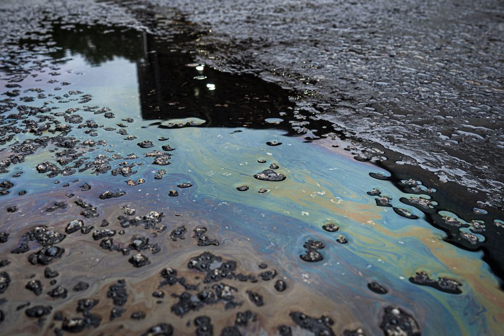 An oil film spreading across standing water on asphalt