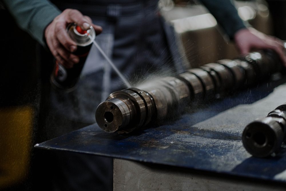 A machined part being sprayed with degreaser on a workshop bench