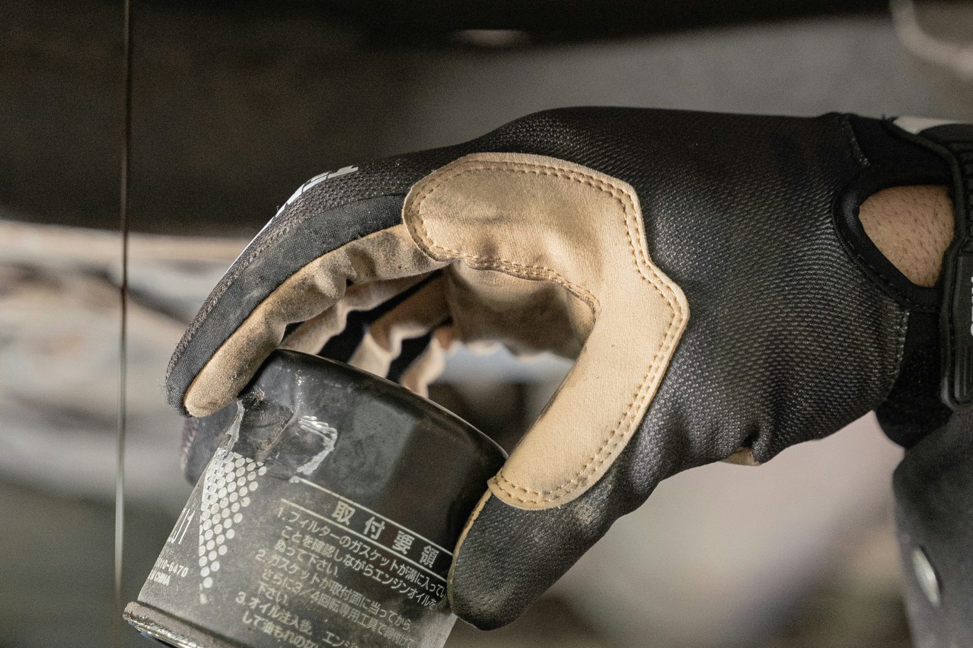 A used oil filter held in a gloved hand